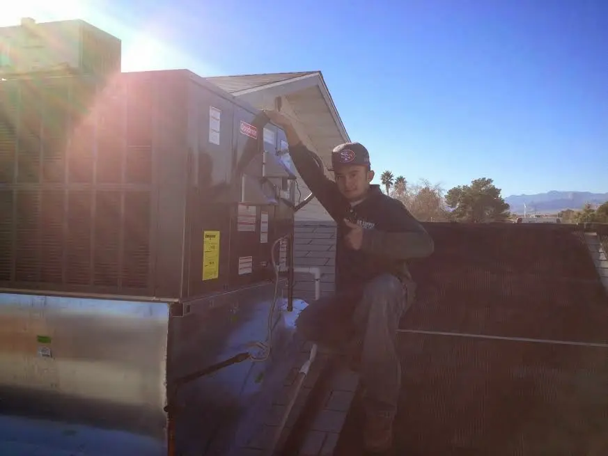 HVAC technician performing AC Tune-Up on a rooftop unit in Pembroke